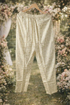 Cream Banarasi ethnic pants with gold motifs displayed outdoors, traditional festive wear