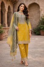 Woman in yellow embroidered ethnic suit with matching dupatta, outdoor heritage setting
