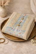 Beige embroidered kurta with pastel blue and gold threadwork, folded on a brass tray