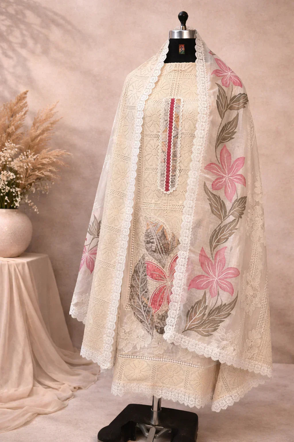 Cream embroidered ethnic suit on mannequin with sheer dupatta, pink floral design, lace border