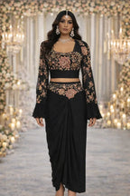 Woman in black floral embroidered ethnic saree gown, accessorized with jewelry, at a festive event.