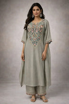 Woman in grey embroidered ethnic kurta set with floral details, matching pants, and dupatta
