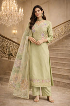 Woman wearing pastel green embroidered ethnic suit with floral dupatta, standing on staircase