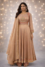 Woman wearing a beige Banarasi Anarkali suit with intricate embroidery, festive ethnic attire