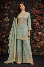 Woman wearing a pastel green ethnic palazzo suit with floral embroidery and matching dupatta